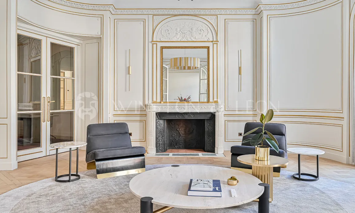 Chic Parisian luxury apartment, Haussmannian living room with gold moldings, marble fireplace & contemporary design furniture.