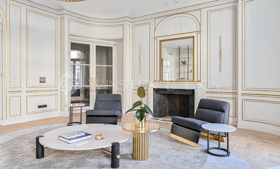 Luxury Parisian Haussmannian living room. Golden moldings, fireplace, contemporary design furniture. Timeless elegance.