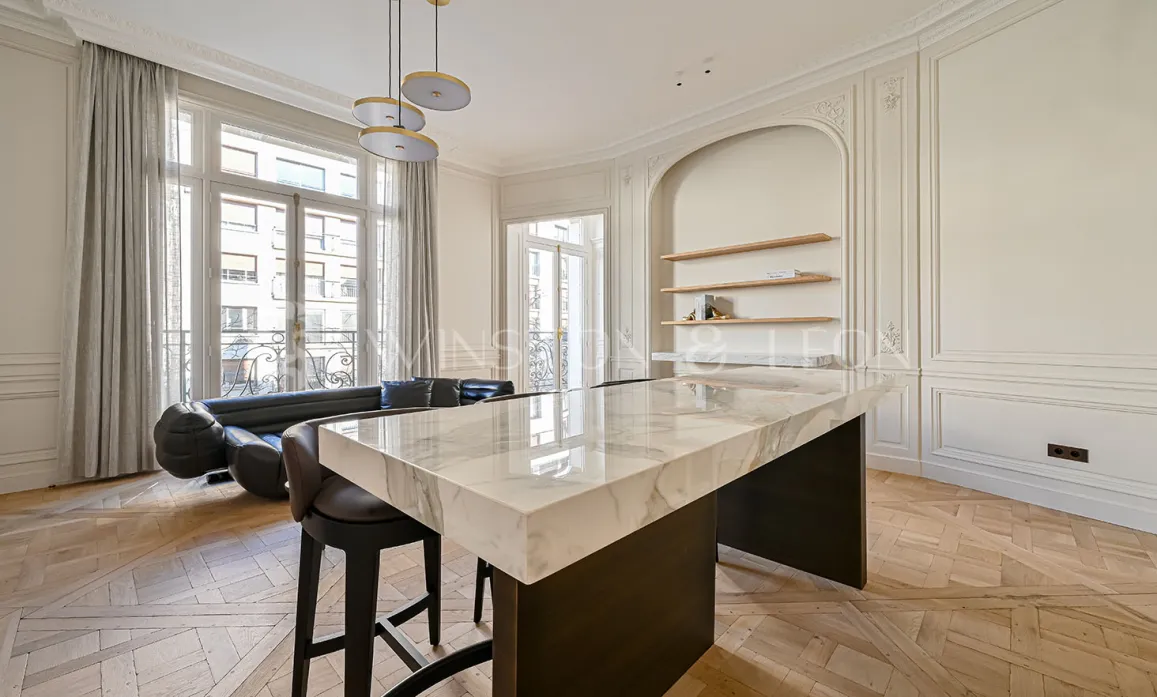 Luxury Parisian apartment with open-plan kitchen, marble island, herringbone parquet, and classic mouldings. Elegant modern design.