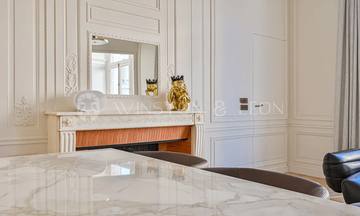Elegant Haussmannian interior: classic moldings, ornate fireplace, mirror, marble table. Refined Parisian luxury, chic design.