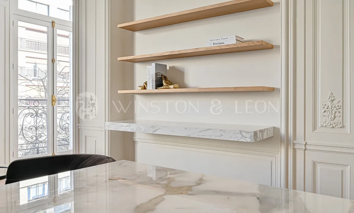 Stunning luxury interior design: marble table, wood shelves, elegant paneling, Haussmannian window. Refinement & brightness for exceptional property.