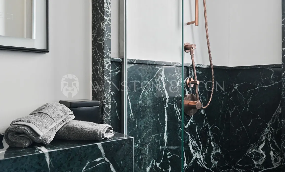 Luxury bathroom with veined green marble and copper fixtures. Elegant shower, contemporary design. Ideal for high-end real estate.