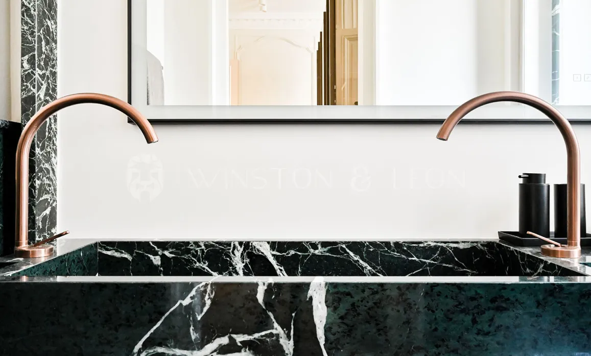 Luxury bathroom: double green marble vanity, designer copper faucets. Modern elegance for a refined interior.
