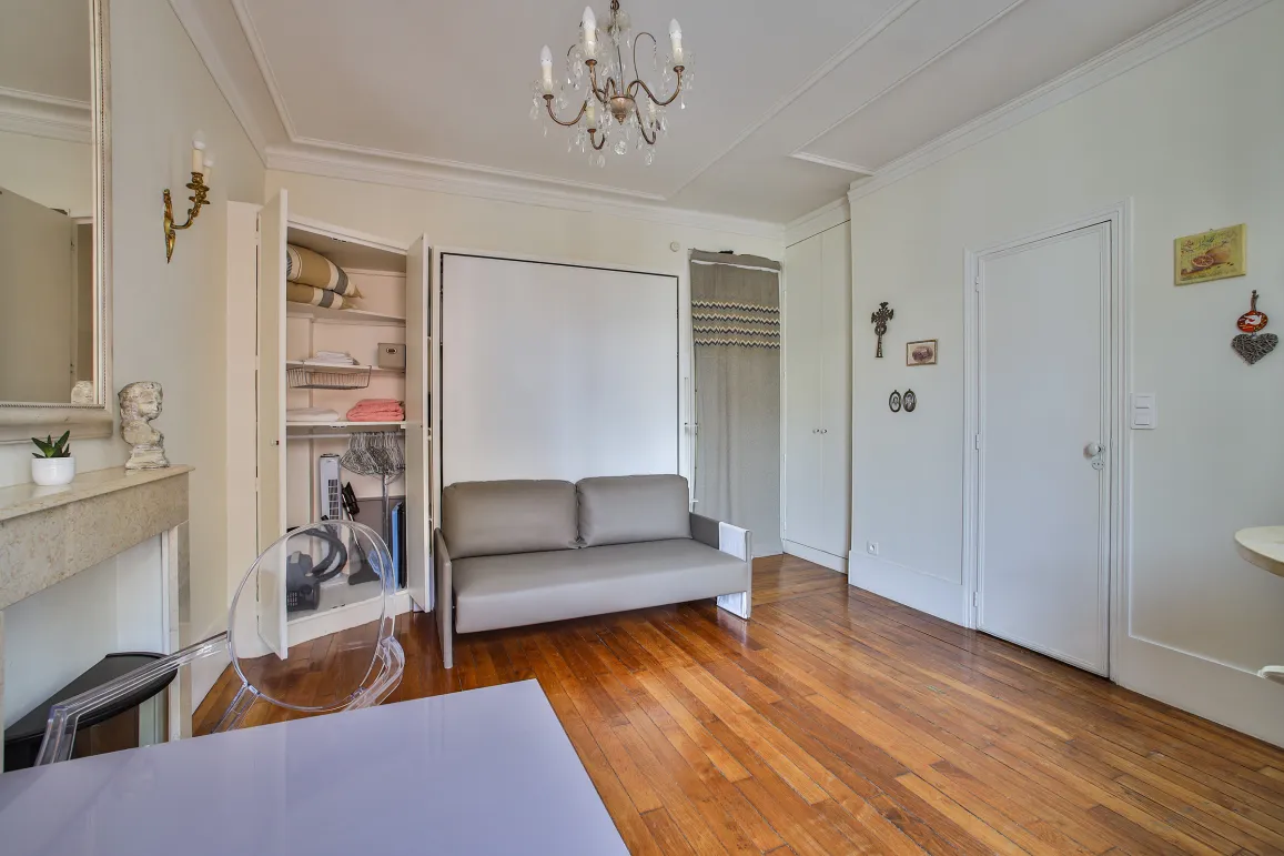 Luxury optimized studio featuring a convertible sofa, hardwood floors, and integrated storage. Parisian elegance & functionality.