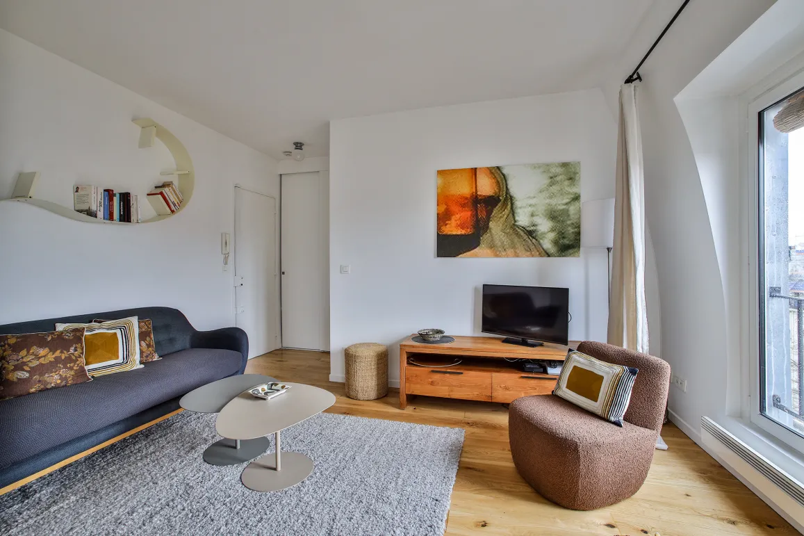 Bright, modern living room featuring designer furniture, contemporary art, and hardwood floors. Refined ambiance for a luxury Parisian apartment.