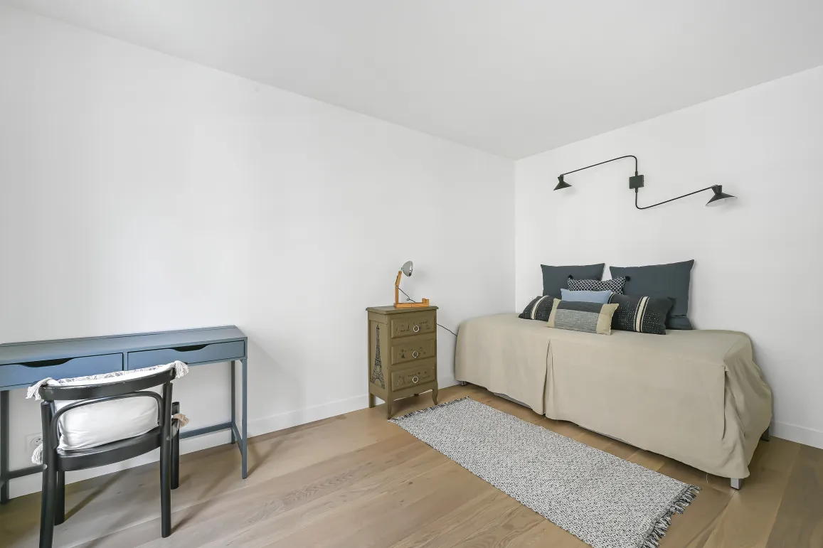 Minimalist, bright bedroom/office. Light wood floor, design bed, elegant desk. Refined versatile space for your luxury property.