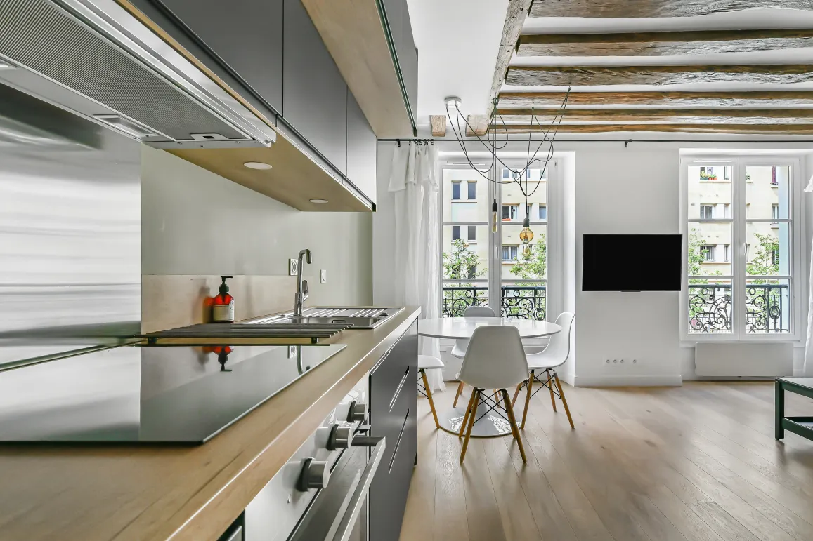 Luxury apartment: modern open kitchen, bright living room, exposed beams, hardwood floors. Parisian elegance.