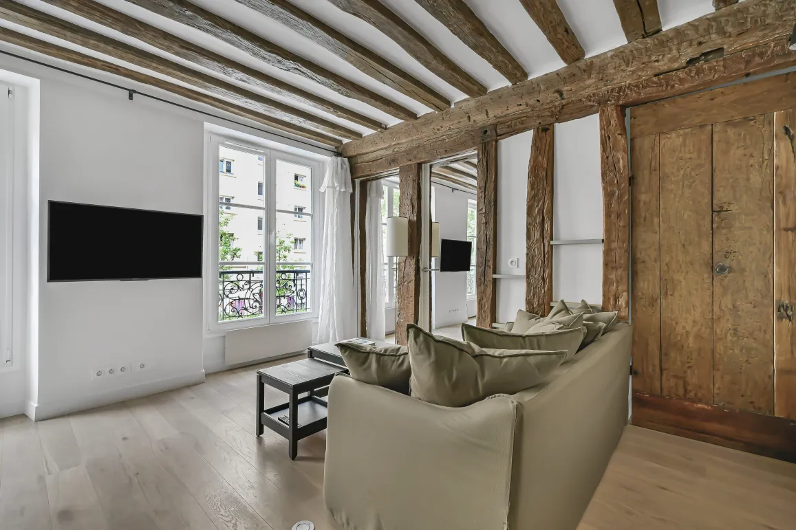 Bright luxury Parisian apartment living room with exposed beams, light wood floor, and modern touches. Charm and elegance.