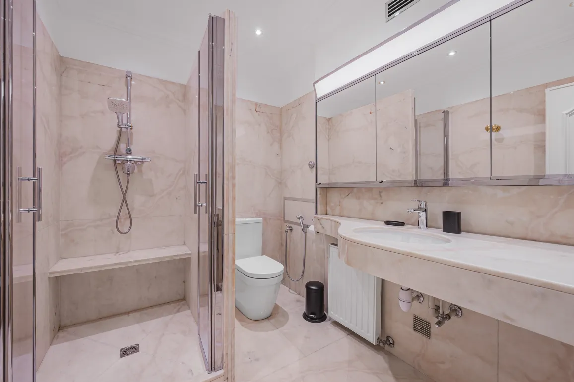 Luxury marble bathroom. Walk-in shower with bench, designer toilet, double vanity. High-end elegance and comfort.