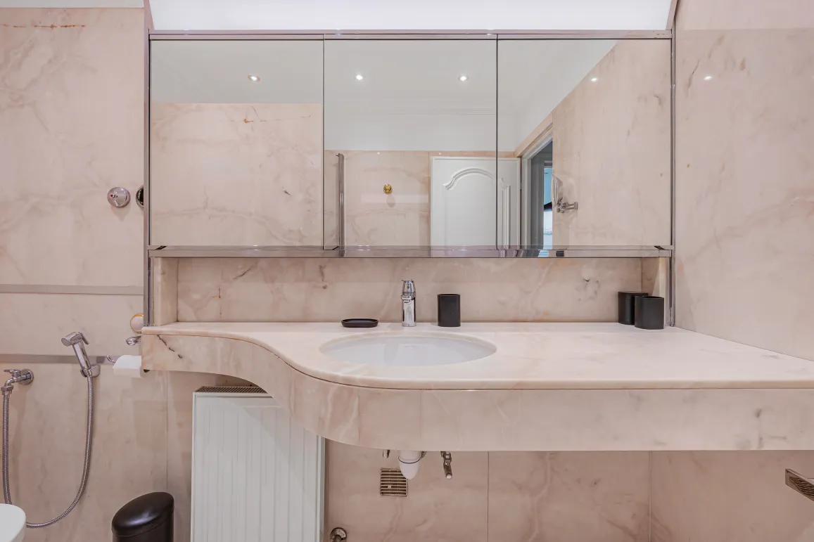 Luxurious light marble bathroom, designer sink and mirror. Refined ambiance for an exceptional property.