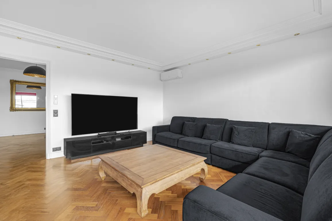 Modern luxury living room with large sectional sofa, TV, herringbone parquet. Comfort and elegance for your home.