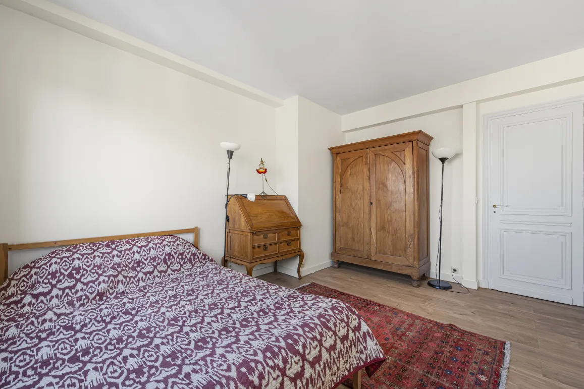 Elegant bedroom with antique solid wood furniture: wardrobe, secretary desk. Comfortable bed, hardwood floor, oriental rug. Timeless charm.