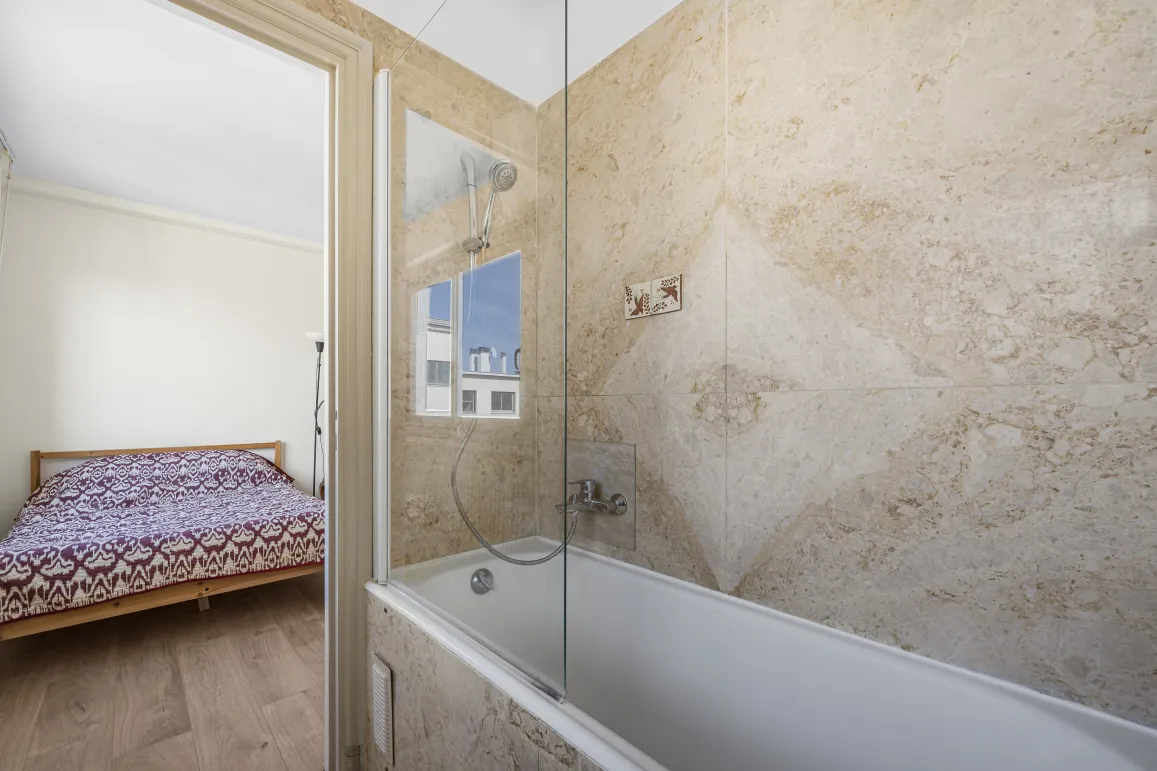 Explore this modern en-suite: bathroom with tub, shower & natural stone walls, opening to a bright bedroom. Functional luxury.