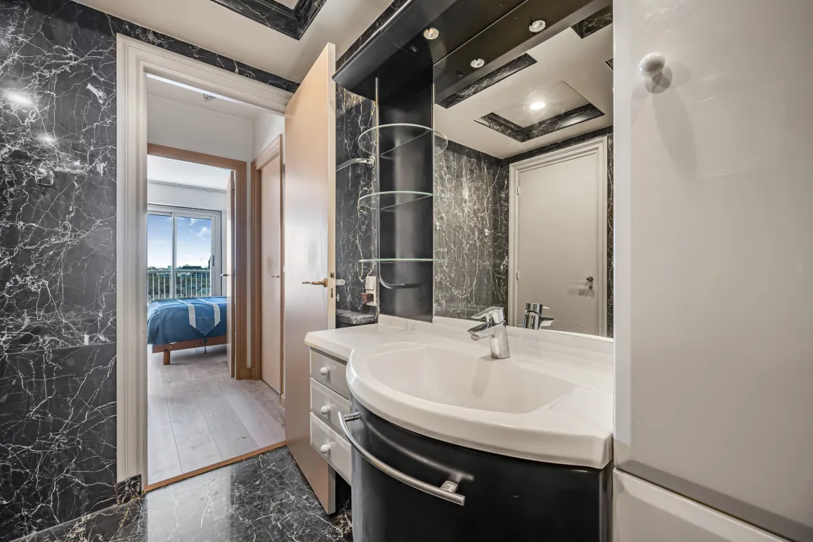 Elegant black marble bathroom, modern design with integrated sink. Access to bright master suite with view. Luxury and comfort.