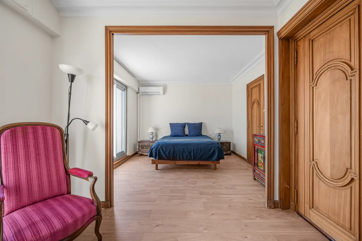 Bright, elegant master suite with blue double bed, light hardwood floors & refined furnishings. A charming luxury property interior.