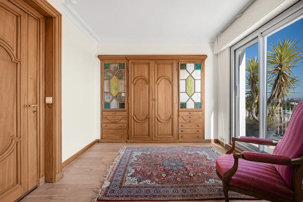 Elegant custom wooden wardrobe with stained glass, parquet floor & oriental rug. Bright terrace access. Chic & warm ambiance.