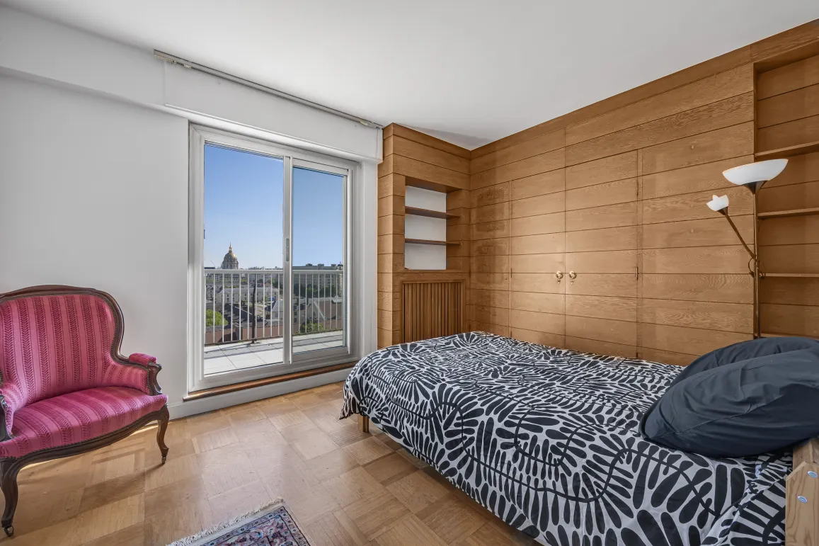 Elegant bedroom with wood paneling, parquet, and balcony offering a breathtaking city dome view. Luxury and serenity at the heart of the apartment.