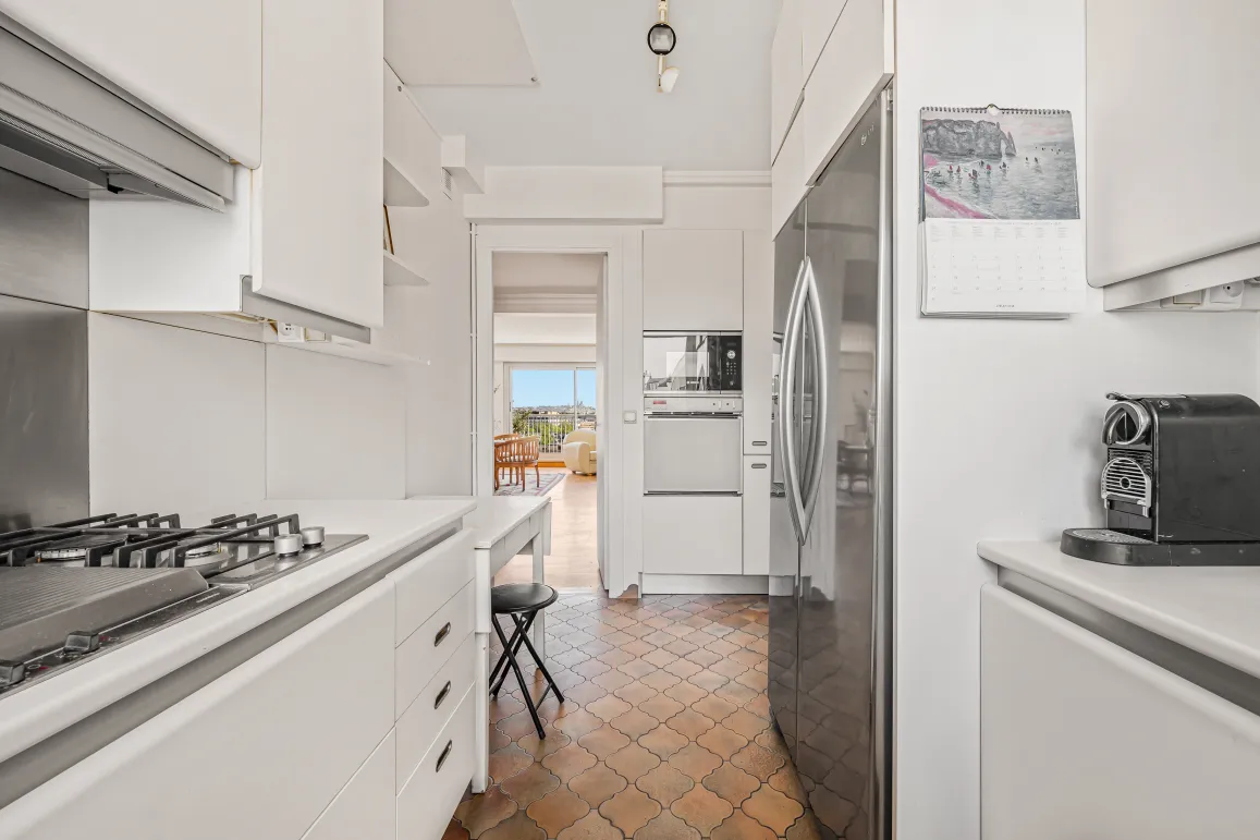 Bright modern kitchen, integrated appliances, unique tiled floor. Open view from living room. Ideal luxury apartment, comfort and style.