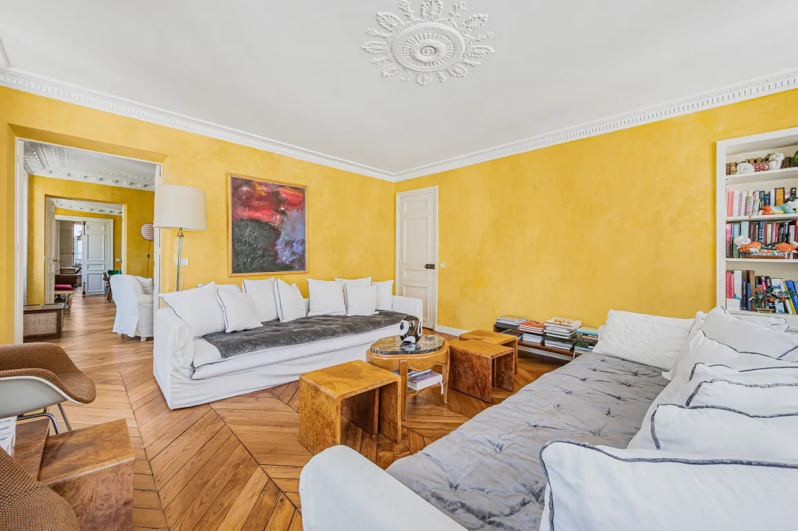 Bright luxury Parisian living room: yellow walls, chevron parquet, moldings, white sofas. Elegance & comfort.