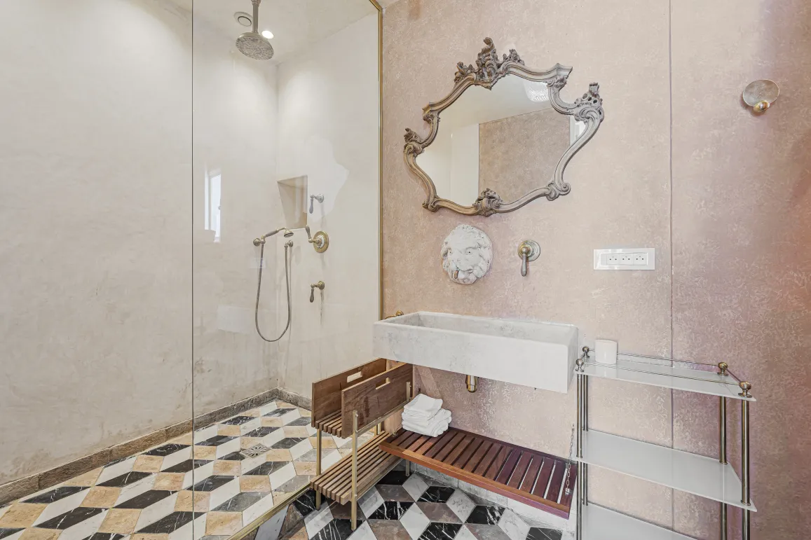 Luxury bathroom. Glass shower, baroque mirror, stone sink, geometric marble floor. Elegant and refined design.