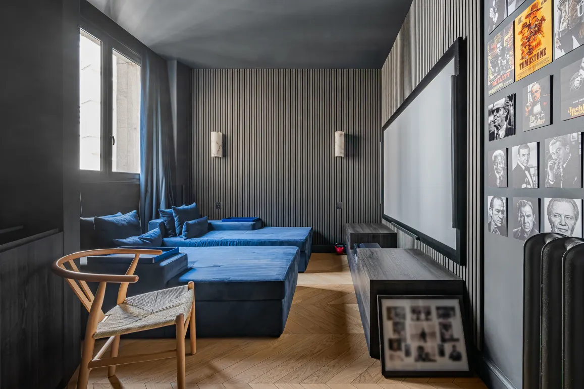 Luxury home cinema: blue velvet seating, large screen, designer walls. Immersive experience for high-end entertainment.
