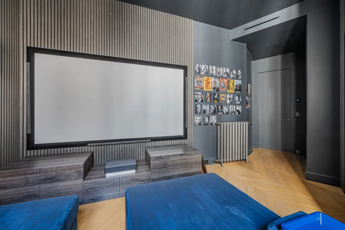 Luxury private home cinema with modern design. Large screen, elegant wood paneling, herringbone floor. Premium immersive experience.