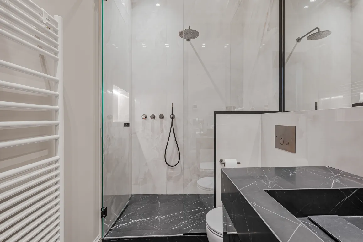 Modern luxury bathroom: walk-in shower with black & white marble, designer vanity, towel warmer. Elegant and comfortable.