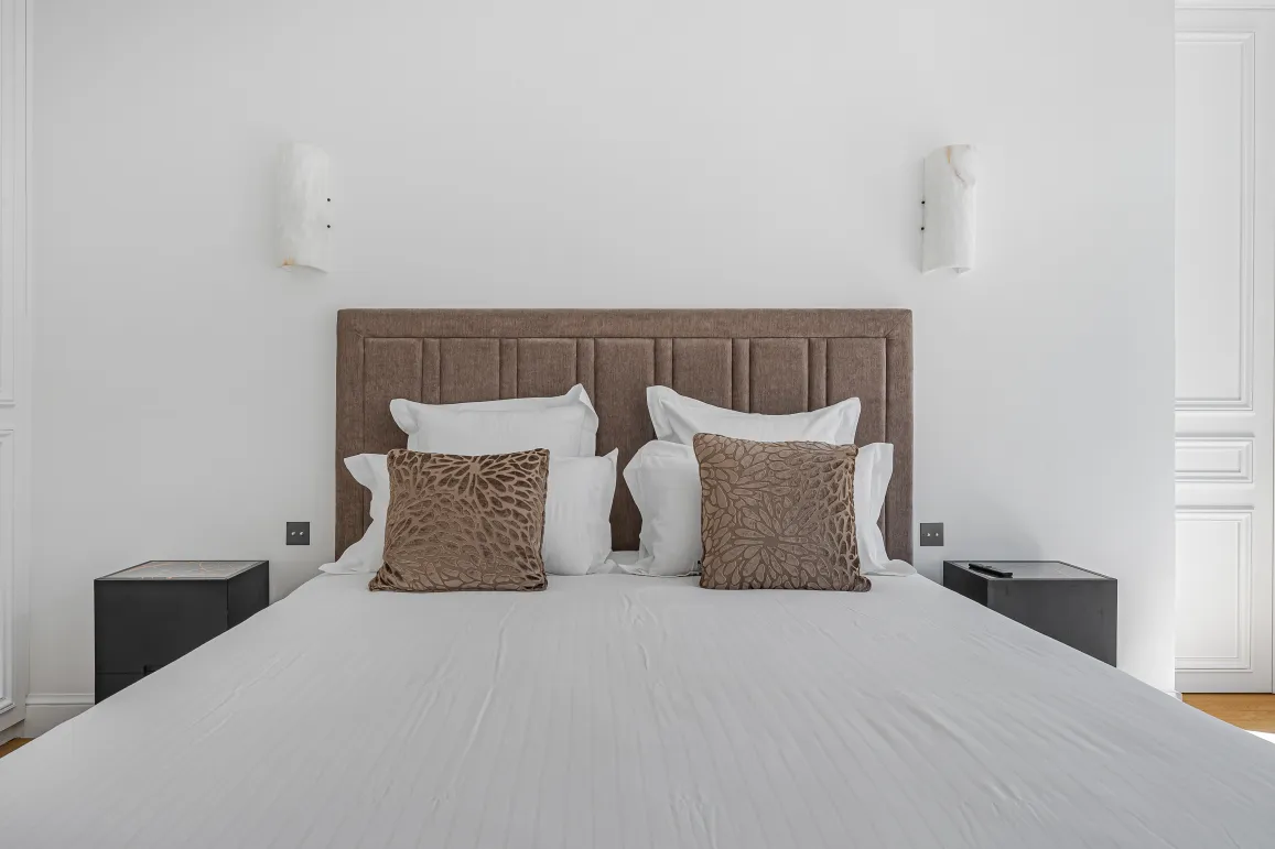 Luxury master bedroom, comfortable double bed with padded headboard, modern and elegant decor. Perfect for a high-end apartment.