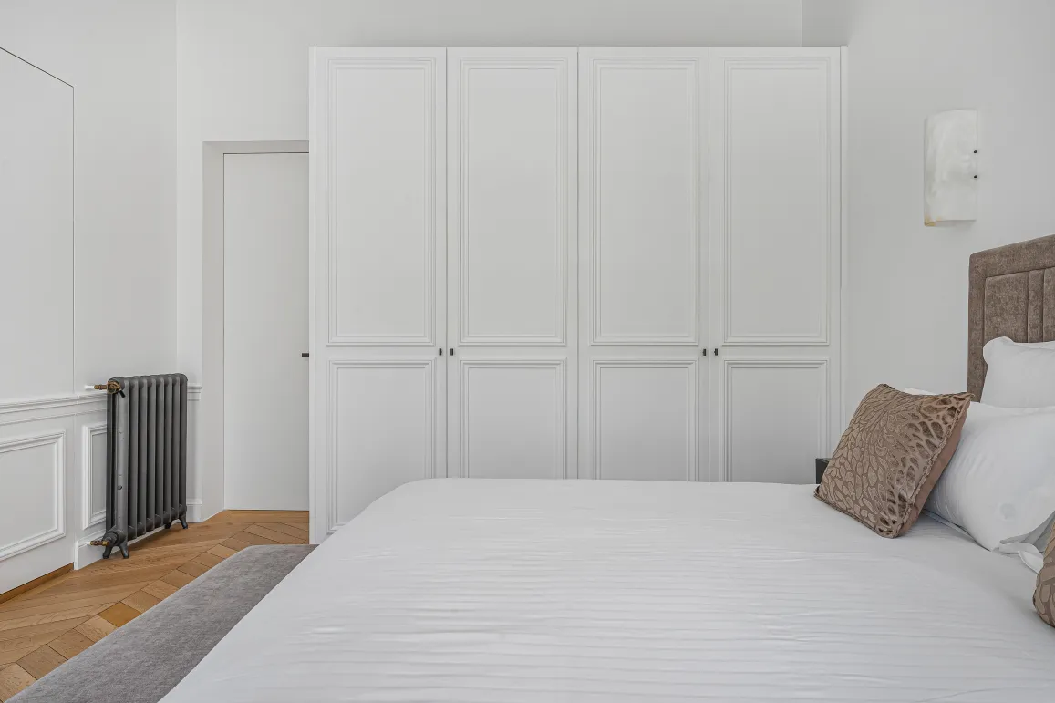 Luxury minimalist bedroom. Built-in wardrobes, comfortable bed, parquet. Contemporary design, elegance & serenity for a master suite.