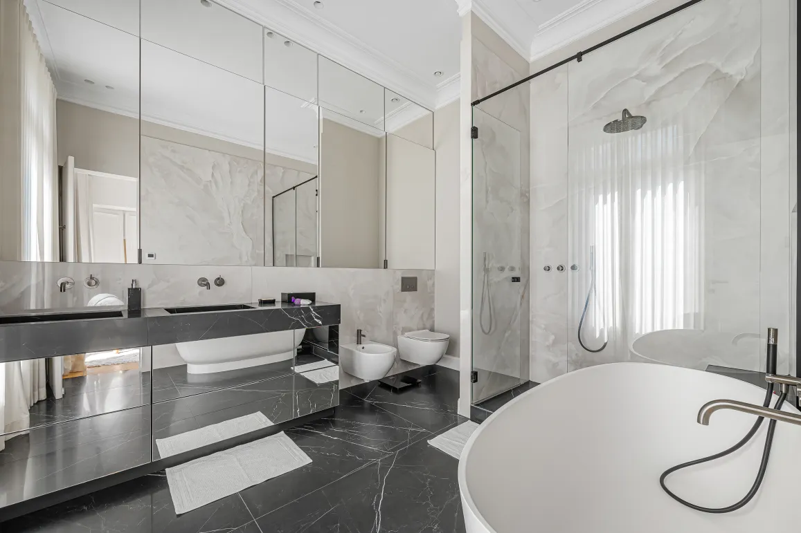 Modern luxury bathroom featuring black and white marble, double vanity, freestanding tub, and walk-in shower. Elegant, high-end design.