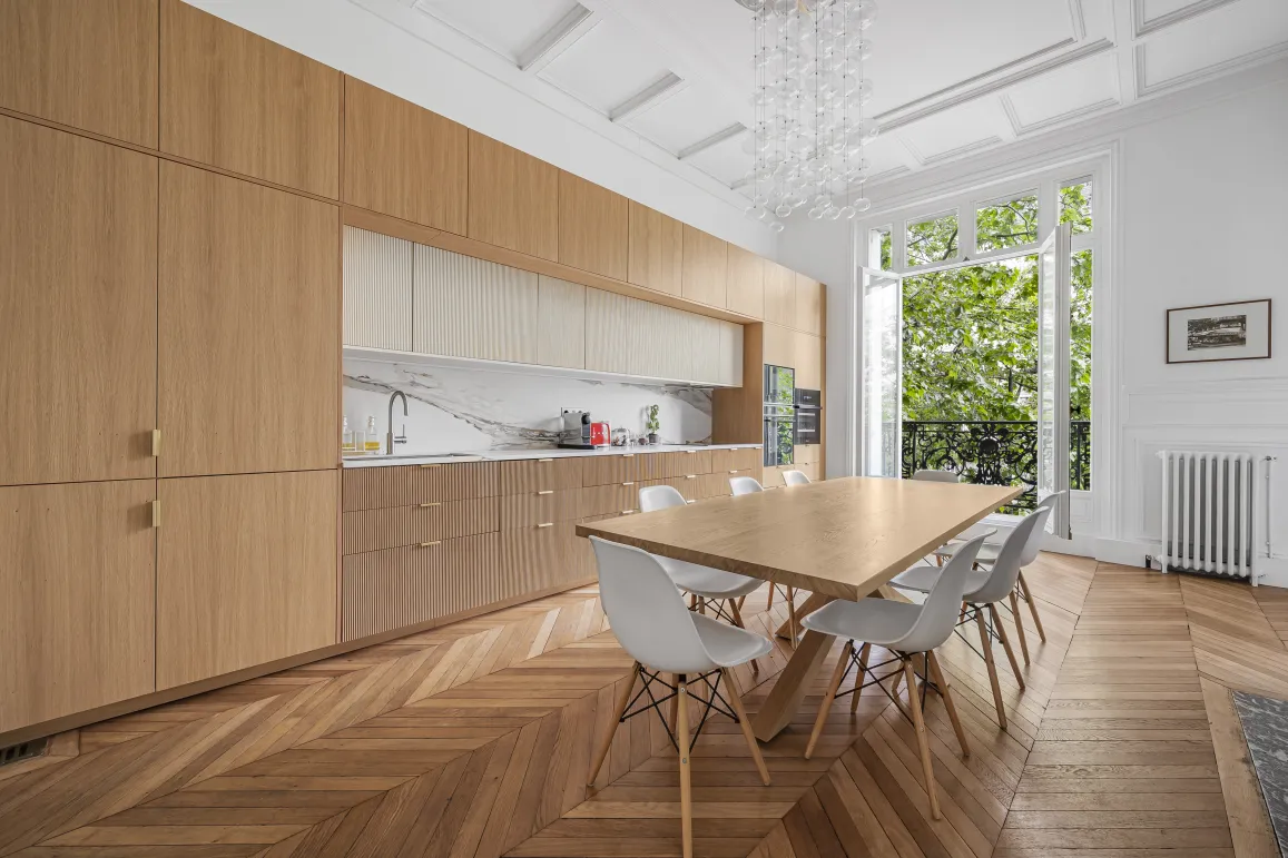 Luxury kitchen dining room, modern elegant design. Parquet flooring, bespoke wood, marble, lush green view. Parisian apartment.
