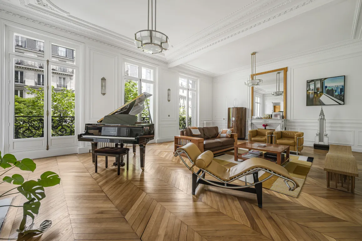 Luxury Parisian living room with grand piano, herringbone parquet, moldings & green views. Timeless elegance & design.