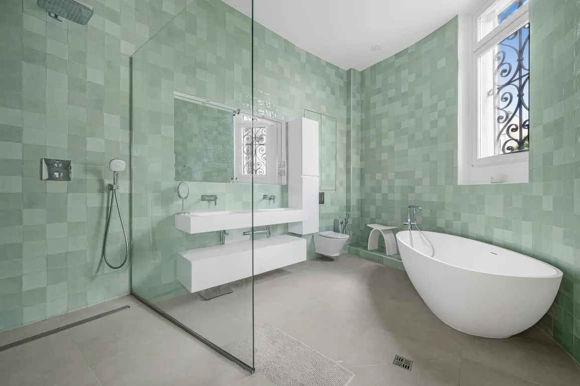 High-end bathroom with sage green zellige tiles, contemporary freestanding bathtub, walk-in shower, and floating double vanity.