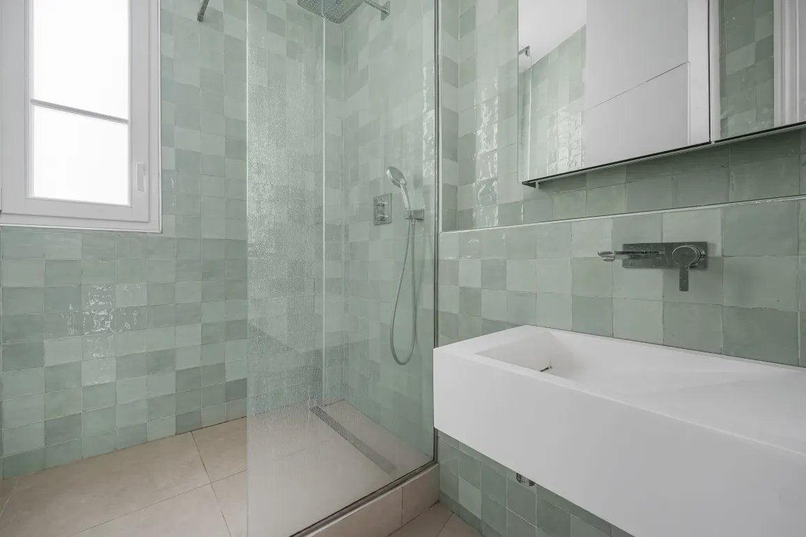 Luxury modern bathroom. Walk-in shower, mint green zellige tiles, designer basin. Elegant and refined design for a high-end interior.