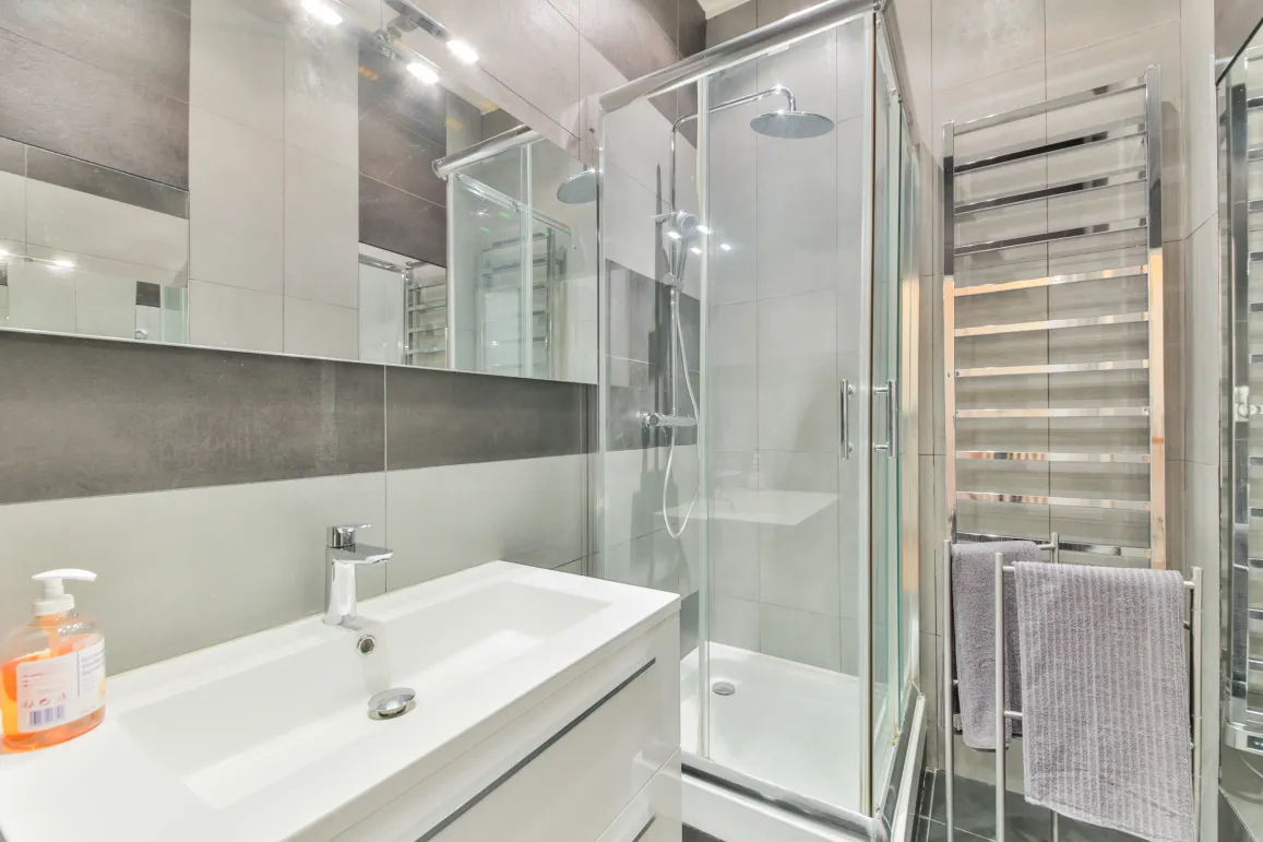 Modern and elegant bathroom with glass shower, designer basin, and chrome towel warmer. High-end finishes for optimal comfort.