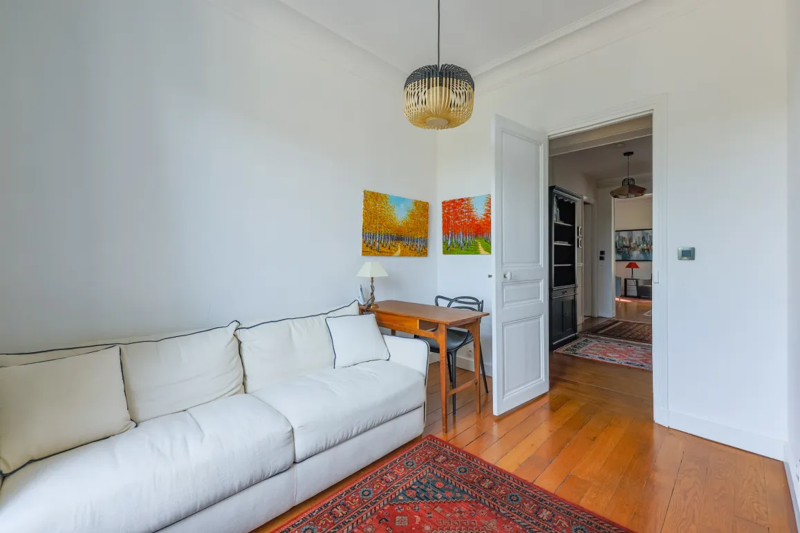 Bright, refined living space: designer sofa, elegant desk, warm hardwood floors, vibrant art. Ideal for a prestigious interior.