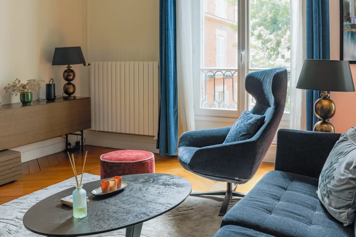 Modern luxury living room: elegant blue designer armchair, comfortable sofa, coffee table, and hardwood floor. Chic, contemporary ambiance.