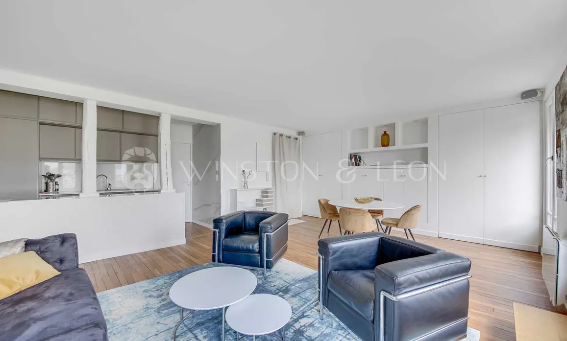 Bright open-plan living and dining room with integrated modern kitchen. Designer furniture, contemporary and refined ambiance for a luxury apartment.