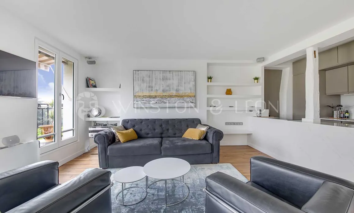 Bright, modern luxury apartment living room with grey sofa, balcony, and open kitchen. Contemporary minimalist design.