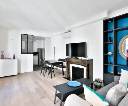 Bright modern living room with open kitchen, fireplace, and vibrant blue built-in shelving. Luxury apartment design.