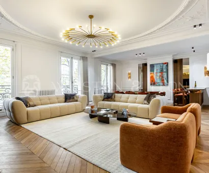 Luxury Haussmannian living room. Contemporary design, herringbone parquet, elegant moldings, and modern chandelier. Prestige apartment.