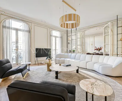 Exceptional Parisian Haussmannian living room: gold moldings, herringbone parquet, white designer sofa, luxury furniture, natural light.