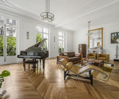 Luxury Parisian living room with grand piano, herringbone parquet, moldings & green views. Timeless elegance & design.