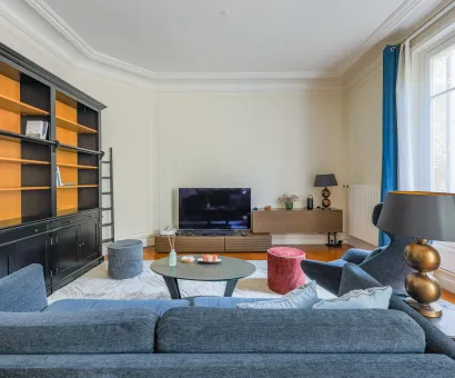 Elegant Parisian luxury living room with built-in bookshelf, designer sofa & TV. Bright and modern apartment space.