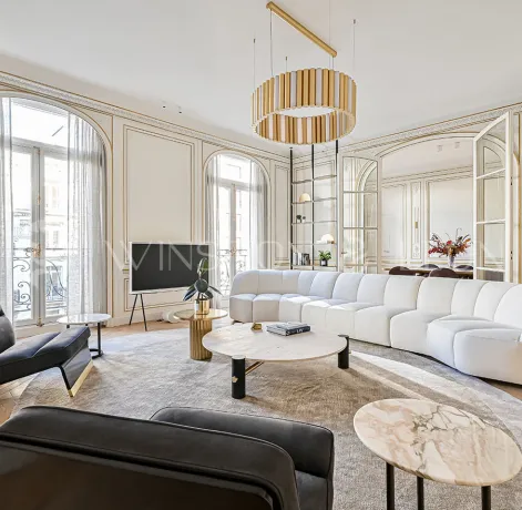 Exceptional Parisian Haussmannian living room: gold moldings, herringbone parquet, white designer sofa, luxury furniture, natural light.