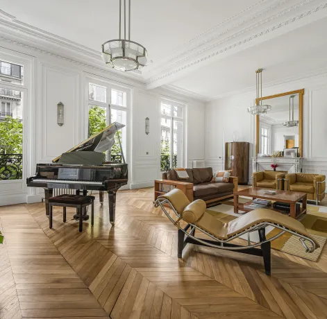 Luxury Parisian living room with grand piano, herringbone parquet, moldings & green views. Timeless elegance & design.
