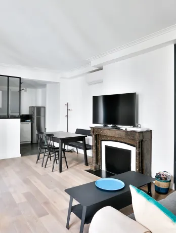 Bright modern living room with open kitchen, fireplace, and vibrant blue built-in shelving. Luxury apartment design.
