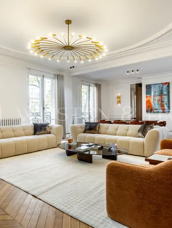 Luxury Haussmannian living room. Contemporary design, herringbone parquet, elegant moldings, and modern chandelier. Prestige apartment.