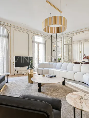 Exceptional Parisian Haussmannian living room: gold moldings, herringbone parquet, white designer sofa, luxury furniture, natural light.